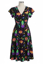 Load image into Gallery viewer, A short-sleeve V-neck dress displayed on a mannequin, featuring a colorful Halloween-themed print with pumpkins, witches, cauldrons, and stars on a black background.