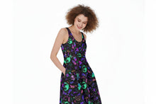 Load image into Gallery viewer, A woman modeling a sleeveless A-line midi dress with a black background and a vibrant, colorful print of skulls, moons, bats, and occult symbols in purple, green, and pink.
