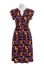 Load image into Gallery viewer, A short-sleeve V-neck dress displayed on a white mannequin against a plain white background. The dress features an all-over Halloween-themed print of purple cartoon bats, yellow crescent moons, and red horizontal stripes on a black base.
